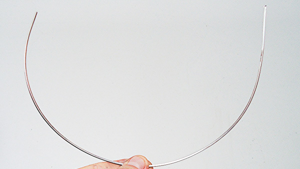 Image: A hand holding up a strand of silver wire.